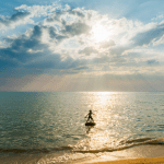 mujer entrando en el mar en el calma cielo con muchas nubes